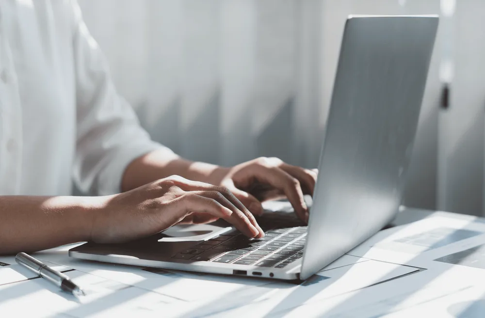 Doigts tapant sur le clavier d'un ordinateur portable
